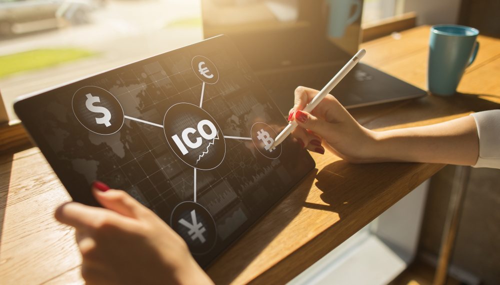 Business professional interacting with a cryptocurrency investment interface on a digital tablet featuring ICO, Bitcoin, and global currencies