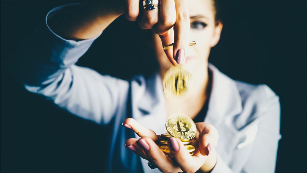 A dynamic image capturing a woman holding a stack of Bitcoin coins, with one coin aligned between her fingers, seemingly in motion. The focused lighting and blurred background emphasize the coins, symbolizing the impact and movement within the cryptocurrency market.