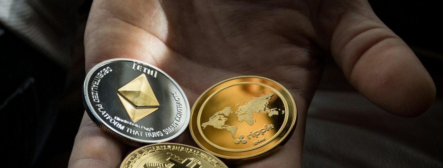 A person's hand presenting a collection of cryptocurrency coins, including Bitcoin, Ethereum, and Ripple, symbolizing personal investment and the diverse portfolio in the digital currency market.