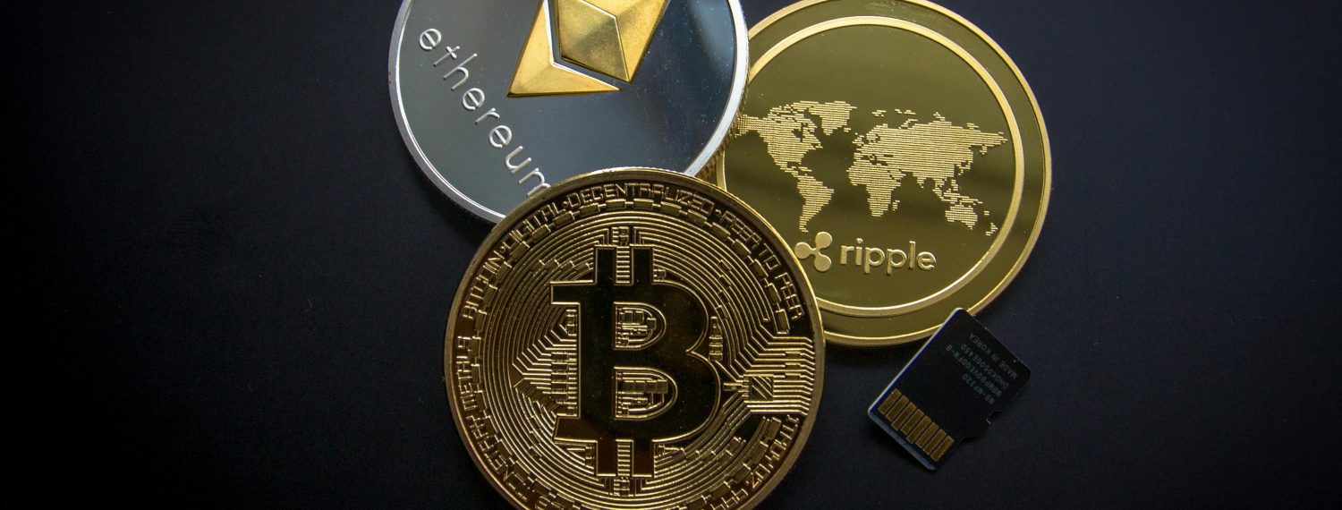 Physical coins representing Bitcoin, Ethereum, and Ripple with a micro SD card on a dark background, symbolizing the tangible aspects of digital cryptocurrencies and secure storage solutions.